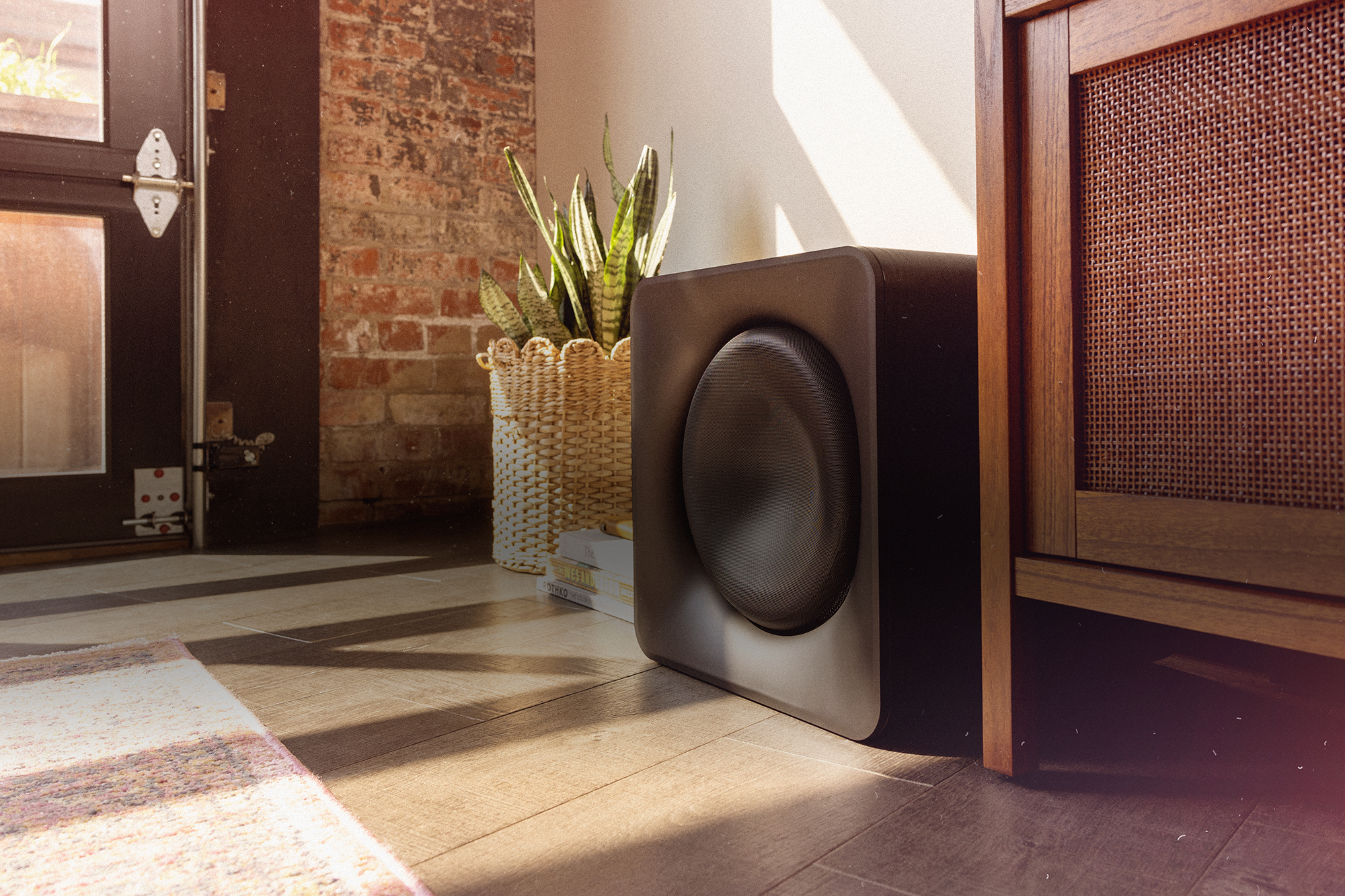Klipsch Flexus SUB 200 in sunny living room beside snake plant in basket and media console 2000x1333
